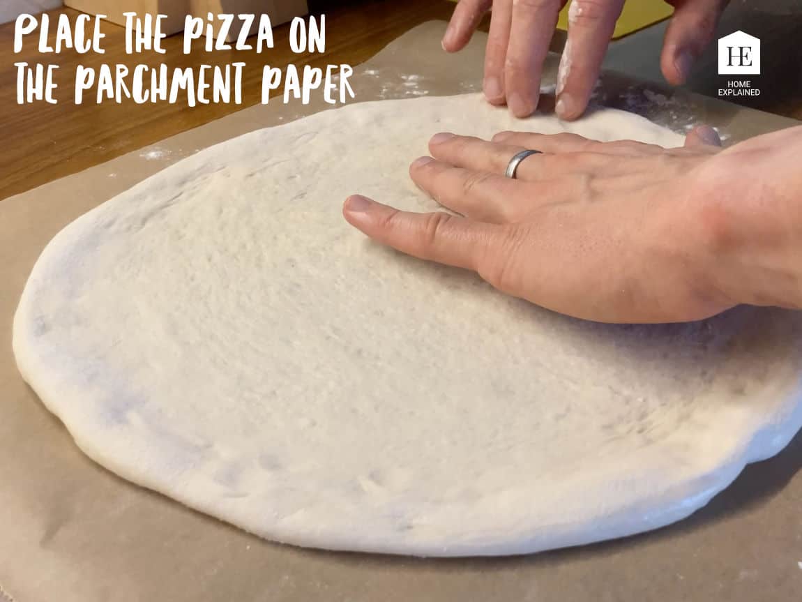 Place the pizza on the parchment paper | HomeExplained.com